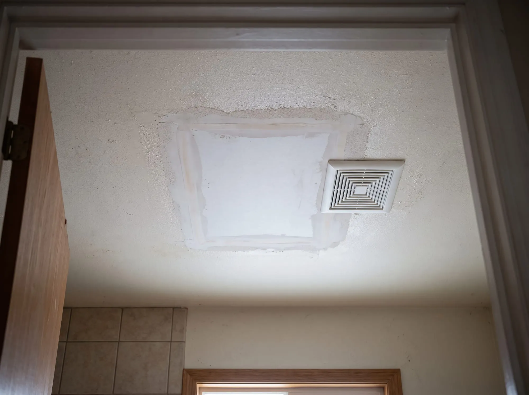 Bathroom ceiling with a replaced drywall section taped and textured to match